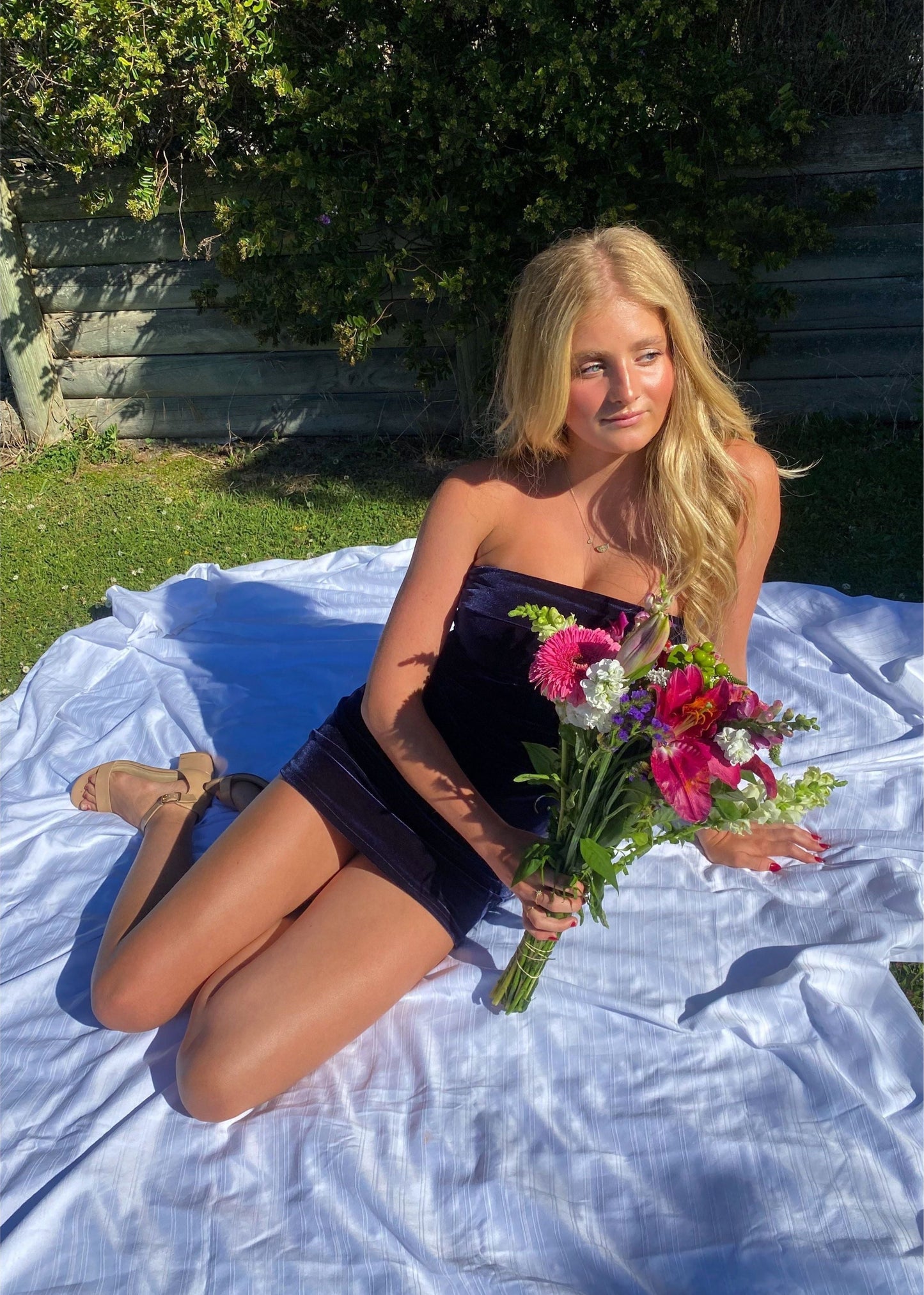 7th and York Strapless Mini Dress in Midnight (Navy), Velvet Material. Perfect for events like the races, birthdays etc. Size 8/S dress. Front on view of sitting down in dress with flowers slightly covering front of dress