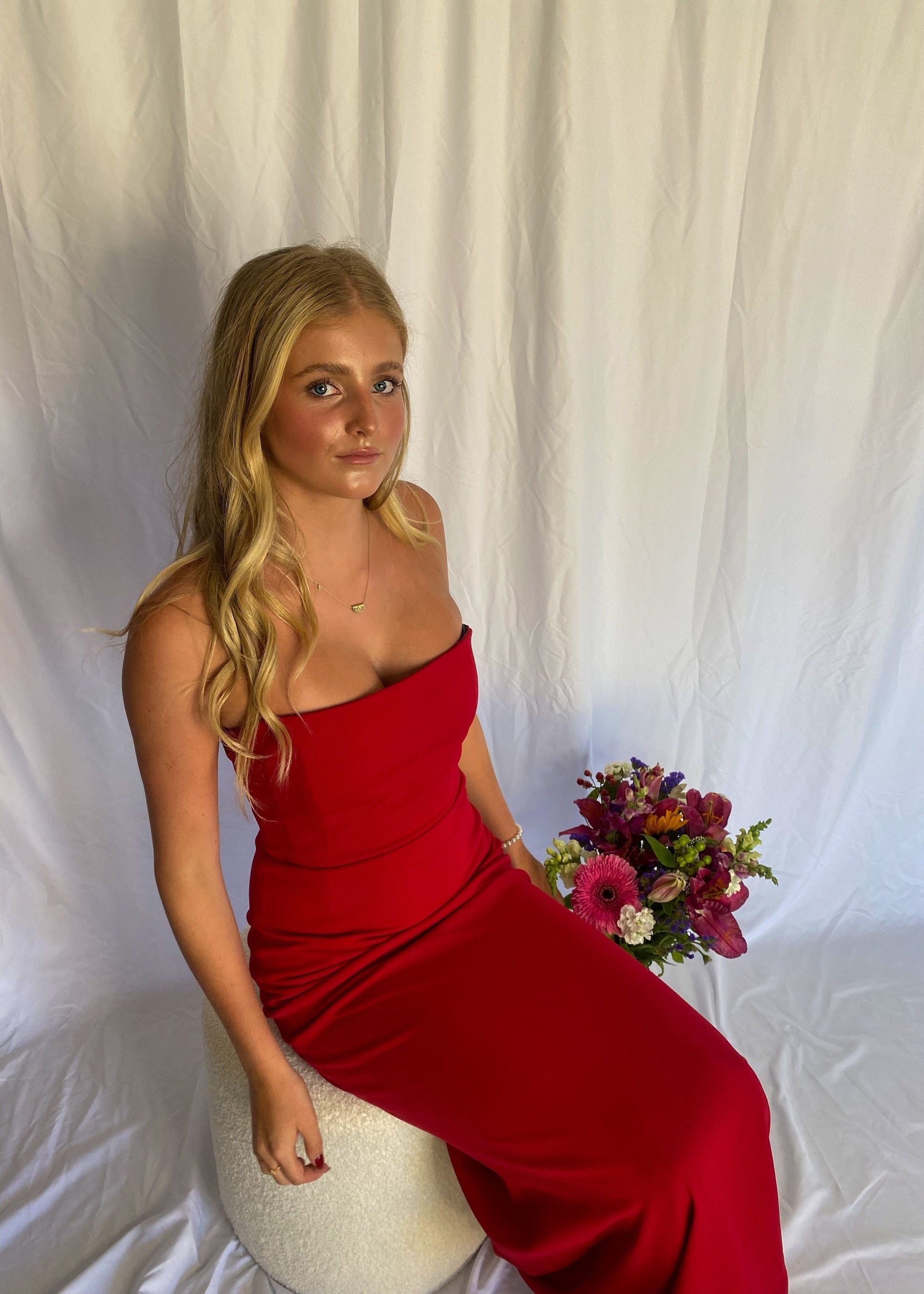Red strapless full length dress. Top bit of dress has boning like a corset an zip up back. Size XS best fitted to a 8 - small 10. Slight above view or dress with person sitting on chair