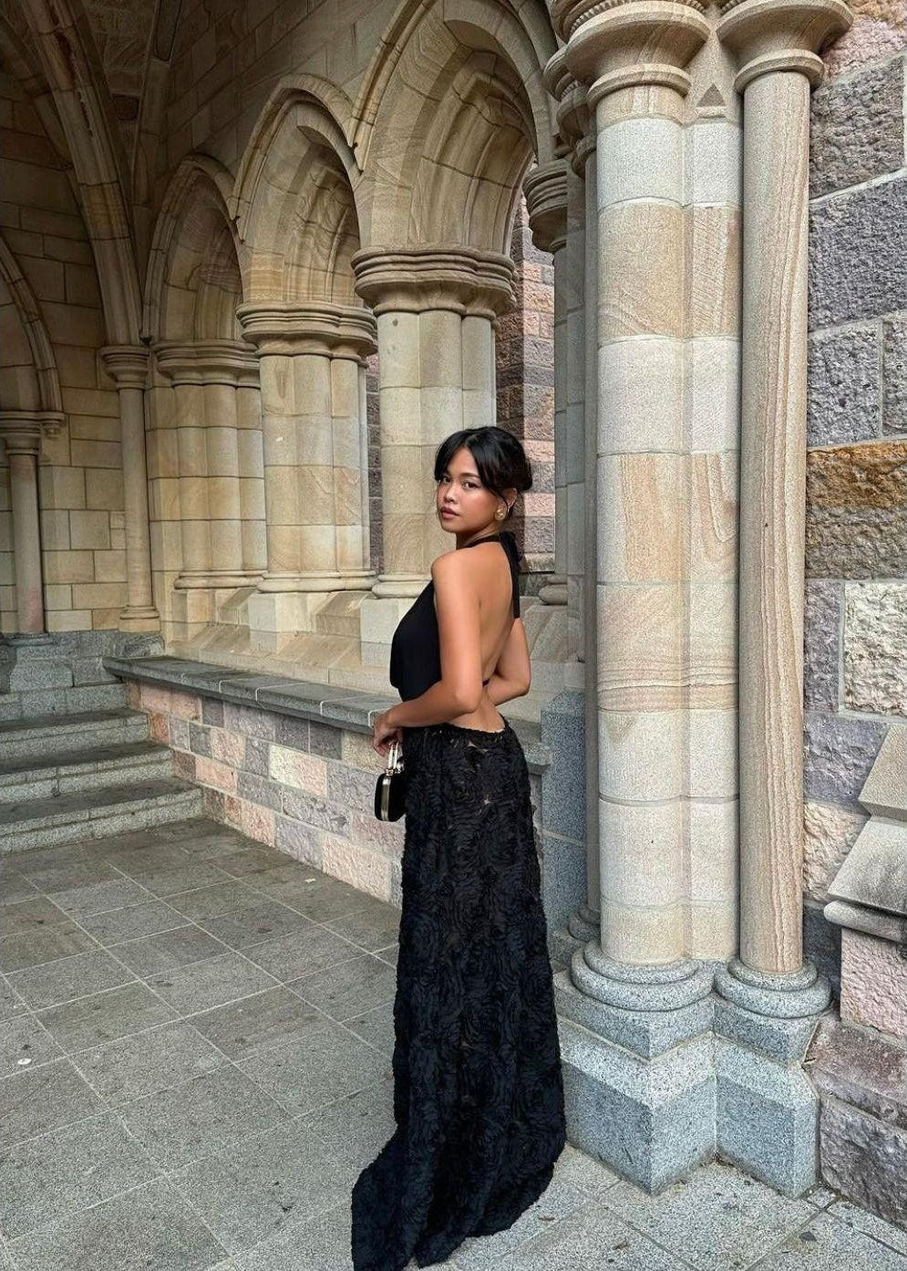 Arcina Ori Adriana Dress in Black, Size M. Low draping front that's is adjustable. Open back with one small strap to connect top area. Skirt flower patterned and is semi sheer. Back side view off dress full length