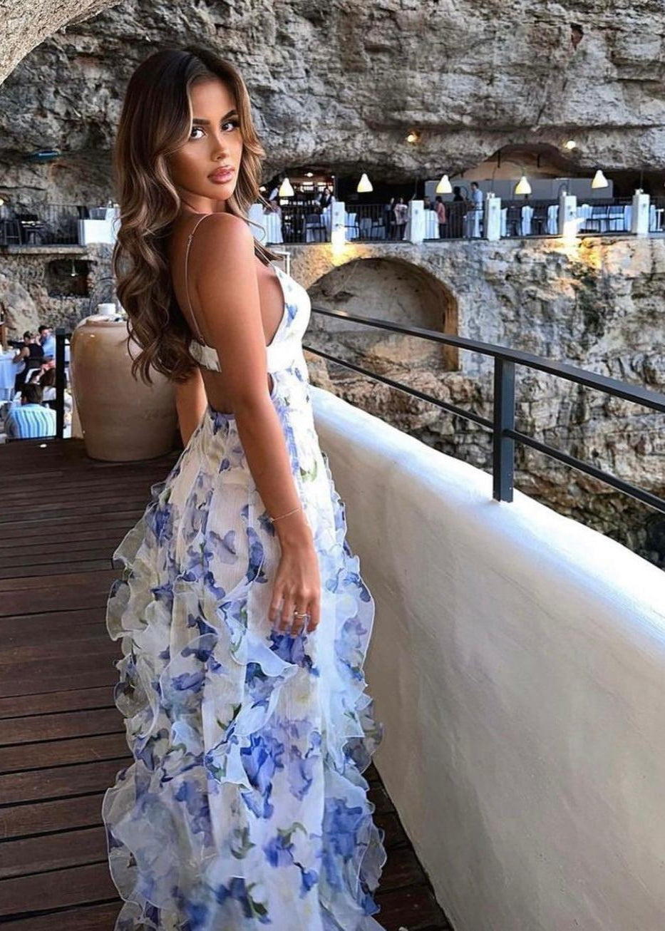 Menti Iris Maxi in Blue Floral is all the way from Greece, Size M. Main colour is semi sheer white with floral patterns of purple/blue with a double lined bust and thin straps. This dress has gorgeoys frills going vertically from hip height to bottom of the dress. It features a mid thigh split for easy movement and is tight fitting on bust/torso when it then starts to flow out. Perfect for formals, races, wineries, birthdays, bottomless brunches etc. Back side view of dress.