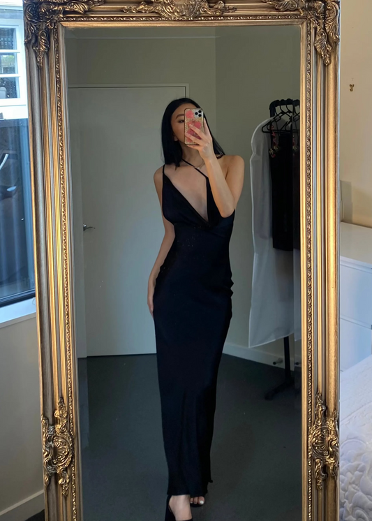 Johannah Cowl Midi in Black, Size 8. Featuring an asymmetrical design with a low cut bust area and low draping back with slight adjustability of strings tying at bottom of back area. Perfect for formal events. Front on view of dress over one shoulder