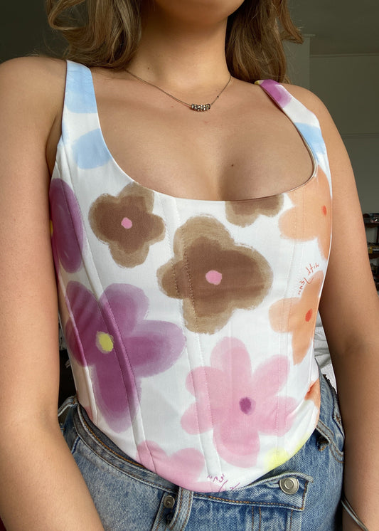With Jean Cindy Corset Top in Viola Tricolour, Size 8/S. The Cindy Corset is a corset style top featuring boning, a curved neckline and hem with a silver hardware zip closure. Scoop neck design. Perfect for more casual events. Front view of top.