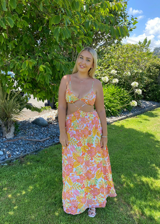 Issy Citrus Aloha Maxi in Floral Print with White, Orange, Pink and Yellow with small hints of green, Size 14. Featuring a lace up back bust area with a open back below with zip on skirt area. Front has stomach cut out with two small straps to attach bust and torso section of dress. Perfect for races, wineries, bottomless brunches etc. Front on full length view of dress.