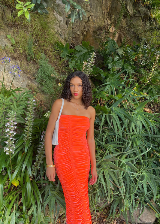 John Christopher Rogers Wiggle Dress in Orange. Best fits a Size 8. Rich velvet material this is a dress to standout in with it's almost fluorescent shade. Strapless design with zip up back. Perfect for formal events where you want to stand out. Front on view of dress.
