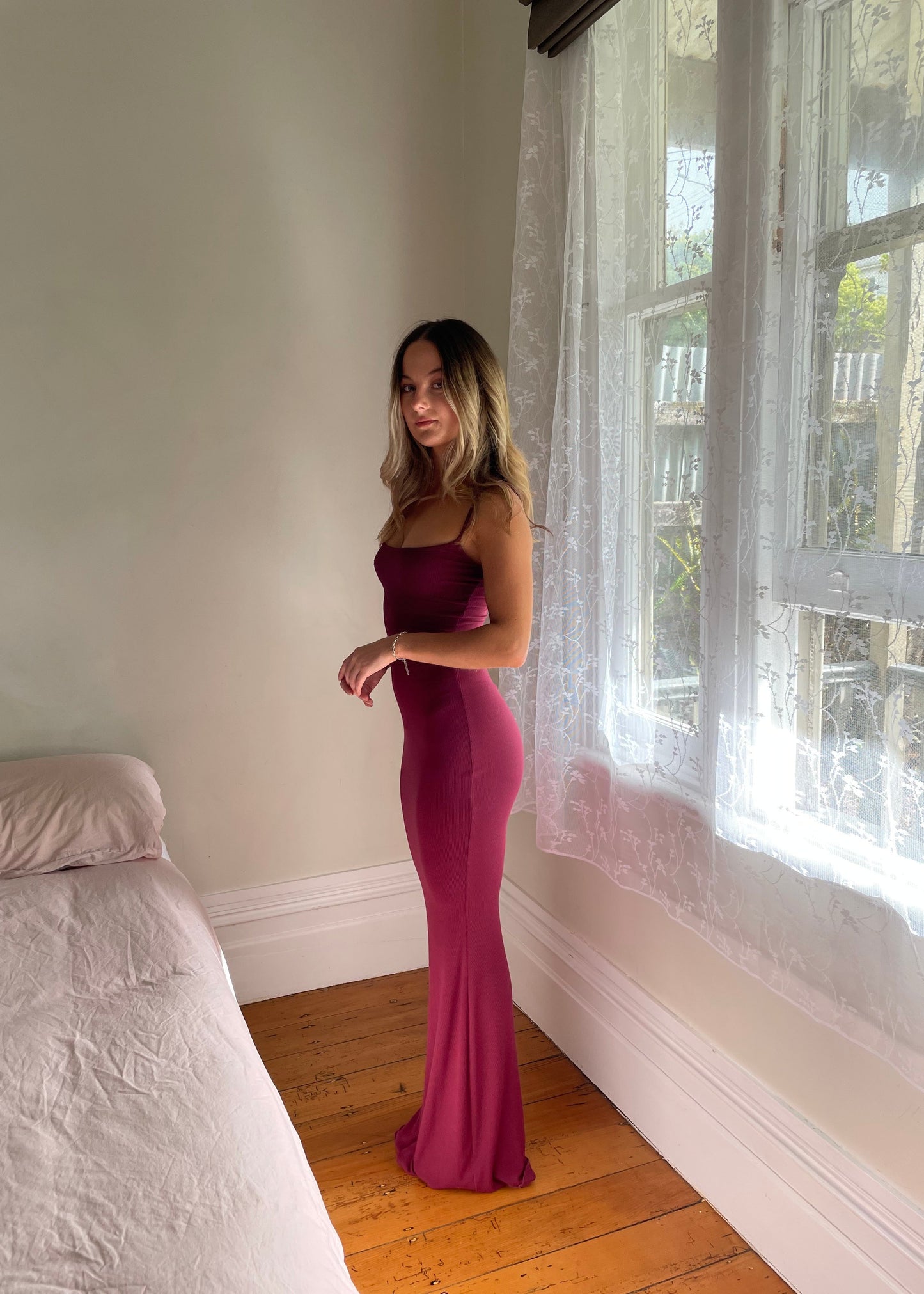 SKIMS Long Slip Dress in Wine Red, Size S. Featuring a body hugging fit, straight neck and adjustable spaghetti straps. Can be dressed up or down. Side on full length view of dress.