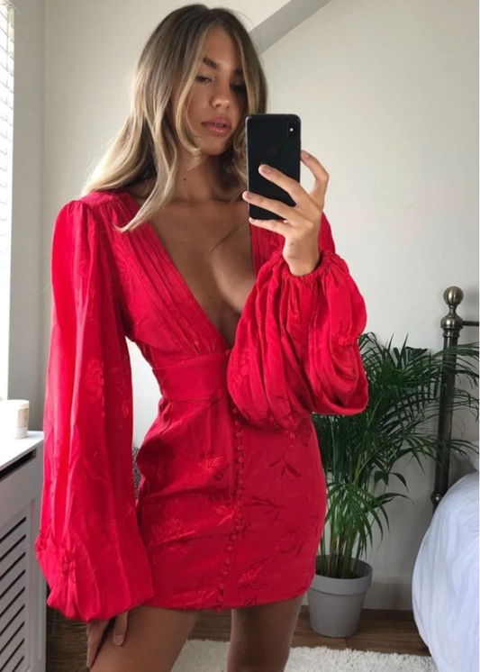 Rat and Boa Isabella Mini Dress in Red, Size XS. Featuring balloon sleeves and a deep v neck with a buttoned front and zip up back. Additionally it features some floral designs in red that give off a slight shine to make it stand out against the red fabric. Perfect for parties, bottomless brunches etc. Front on view of dress.