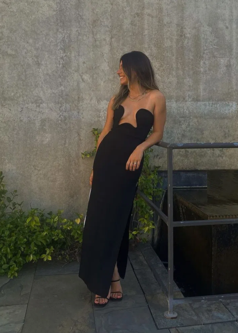 Morocco Maxi Dress in Black, Size XS and L. Featuring a unique strapless design with a zip up back and cut out area in middle of bust. This is a tight fitting dress. Split up side of dress ending mid thigh to make walking easier. This dress is best for formal events. Front on view of dress