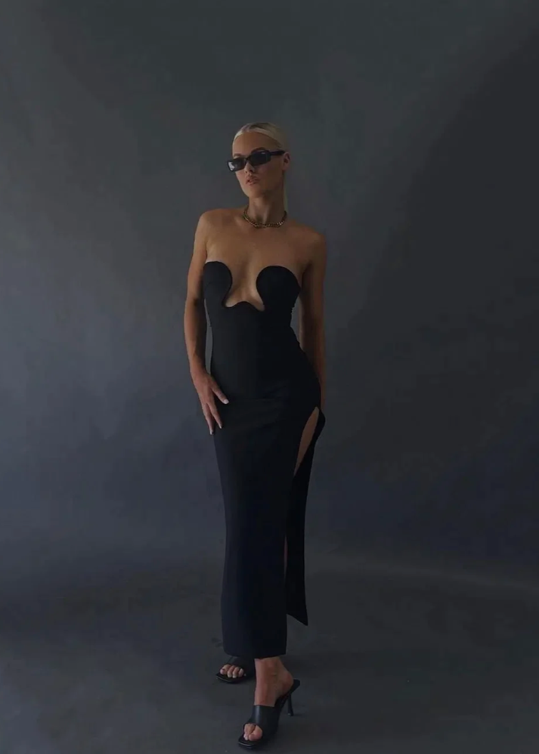 Morocco Maxi Dress in Black, Size XS and L. Featuring a unique strapless design with a zip up back and cut out area in middle of bust. This is a tight fitting dress. Split up side of dress ending mid thigh to make walking easier. This dress is best for formal events. Front on view of dress