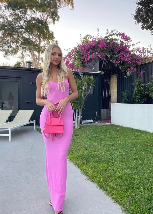 SKIMS Long Slip Dress in Bubblegum Pink, Size M. Featuring a body hugging fit, straight neck and adjustable spaghetti straps. Can be dressed up or down. Dress can appear semi sheer depending on how much it is stretched when on. Can be dressed up or down. Front on full length view.
